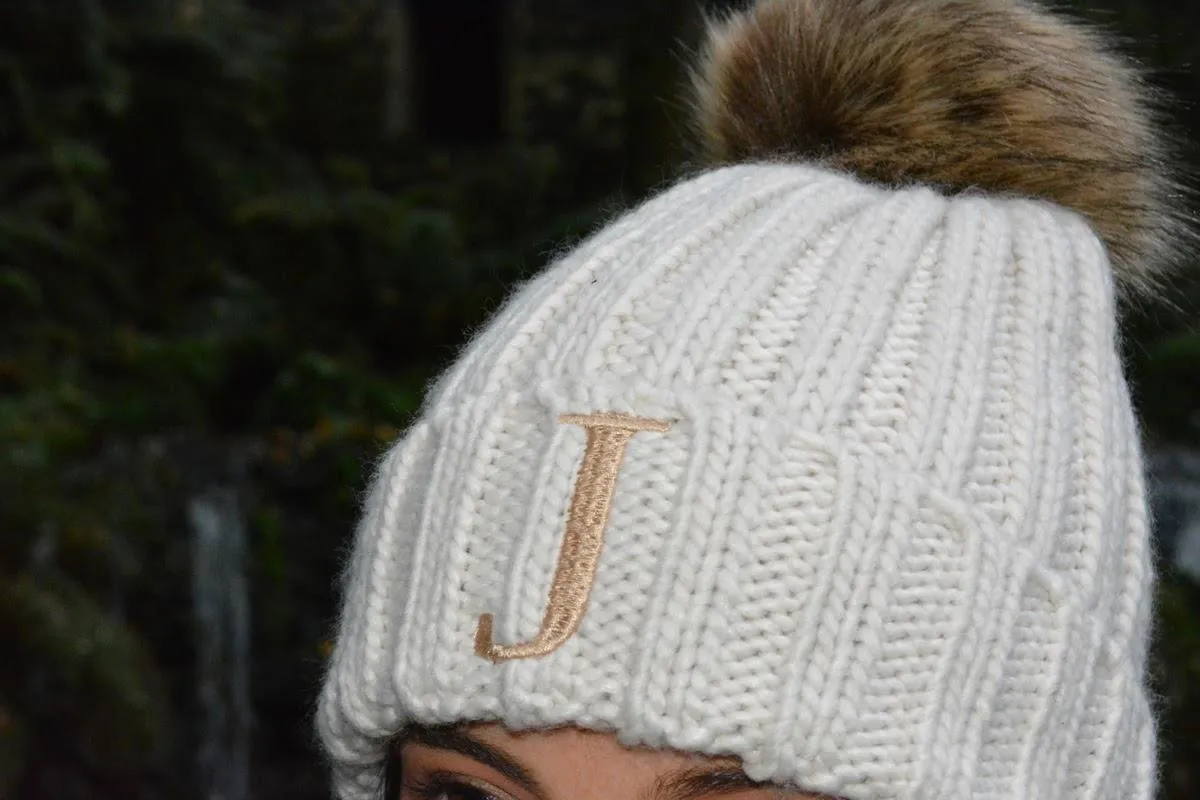 GORRO JUNIOR CON POMPóN DE PELO SINTéTICO COLOR BEIG  INICIAL BORDADA